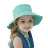 Une-petite-blondinette-souriente-porte-un-bob-enfant-turquoise-image-sur-un-fond-blanc