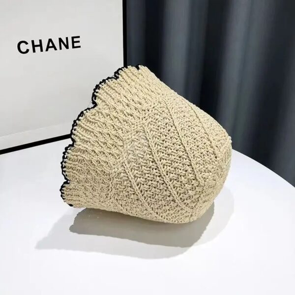 bob-chapeau-pour-la-plage-en-paille Un bob en paille couleur beige renversé sur le côté posé sur une table blanche