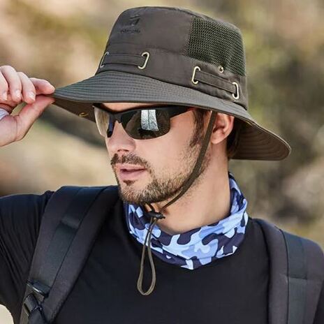 bob-chapeau-de-pecheur-confortable Un homme de profil avec des lunettes noires de soleil porte un joli chapeau bob pêche couleur marron sur la tête sur un décor de nature flouté