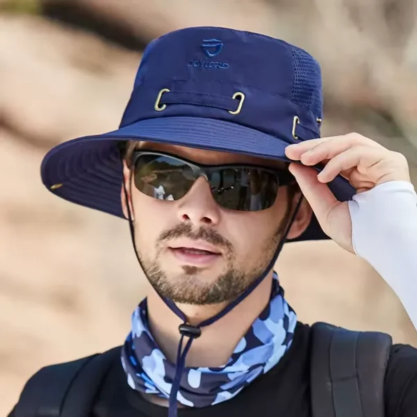 bob-peche-homme-femme Un modèle avec des lunettes noires de soleil porte un joli chapeau bob pêche couleur bleu marine sur la tête sur un décor de nature flouté