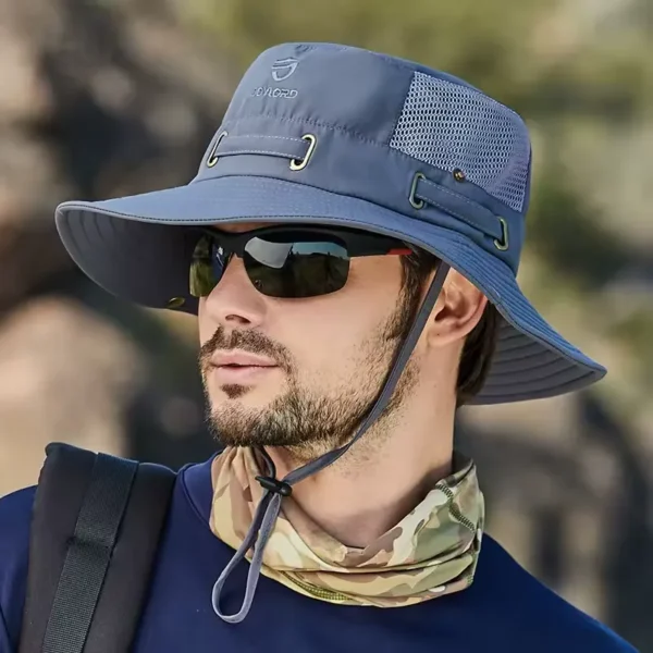 bob-pecheur-homme-et-femme Un modèle de profil avec des lunettes noires de soleil porte un joli chapeau bob pêche couleur grise sur la tête sur un décor de nature flouté