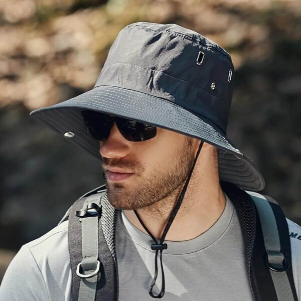 bob-safari-homme-gris Un homme porte un bob safari gris foncé avec des lunettes de soleil en plein air