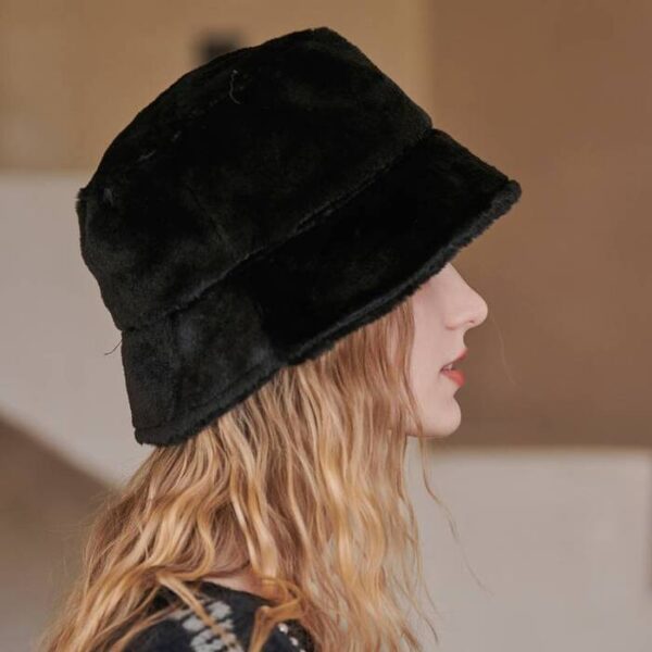 chapeau-bob-hiver-femme-noir Un modèle porte un bob chapeau noir en fourrure épais et doux de profil avec un décor doux marron flouté