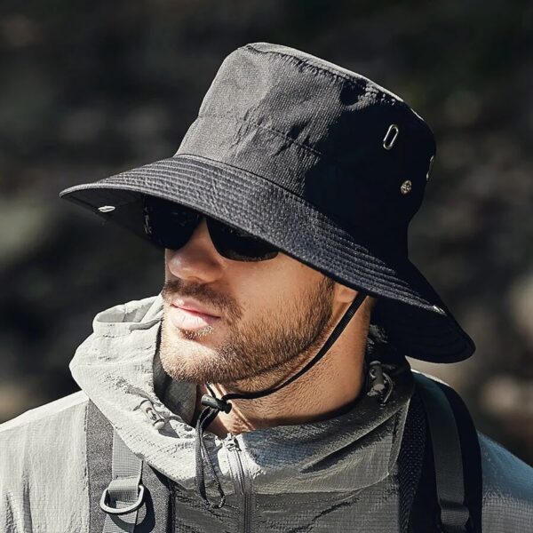 chapeau-bob-noir-safari Un homme porte un bob safari noir avec des lunettes de soleil en plein air