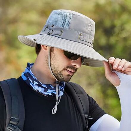 chapeau-bob-peche Un modèle de profil avec des lunettes noires de soleil porte un joli chapeau bob pêche gris clair sur la tête sur un décor de nature flouté