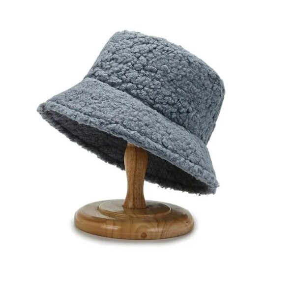 chapeau-de-pecheur-laine Un chapeau bob bleu en laine de mouton est posée sur un support en bois sur un fond blanc