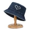 Bob en jean bleu marine avec un dessin de cœur présenté sur un support à chapeau en bois