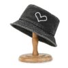 Bob en jean noir avec un dessin de cœur présenté sur un support à chapeau en bois