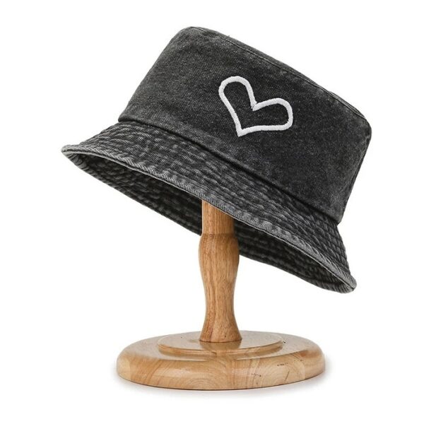 Bob en jean noir avec un dessin de cœur présenté sur un support à chapeau en bois