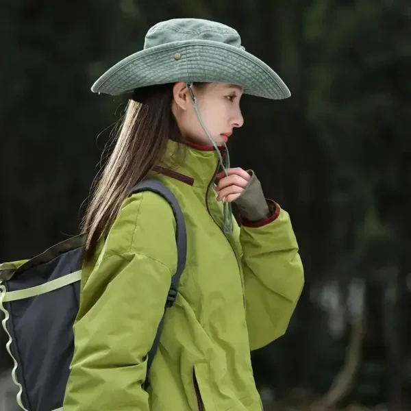 Une femme de profil porte un bob chapeau style cowboy vert avec ficelle sur un décor de nature