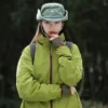 Une femme de face porte un bob chapeau style cowboy vert avec ficelle sur un décor de nature