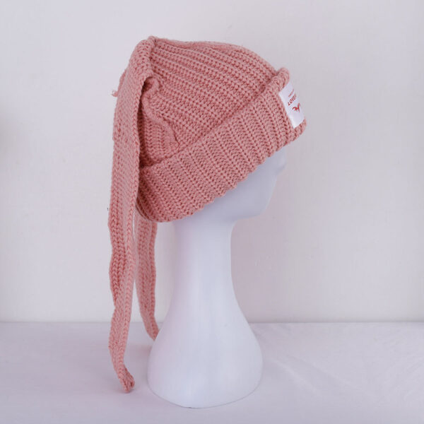 Le bonnet avec oreilles de lapin rose est présenté de profil sur sa tête de mannequin en plastique