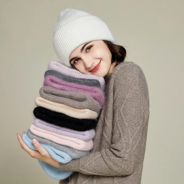bonnet-epais-fourrure-femme Fille souriante porte un bonnet épais et doux pour l'hiver et porte aussi une pile d'autres bonnets de différentes couleurs pliés