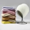 bonnet-epais-hiver-chauf-femme Un bonnet chapeau femme blanc sur son porte chapeau en métal avec une pile d'autres bonnets de différentes couleurs à côté