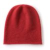 Un bonnet en cachemire de couleur rouge est présenté à plat sur un fond blanc