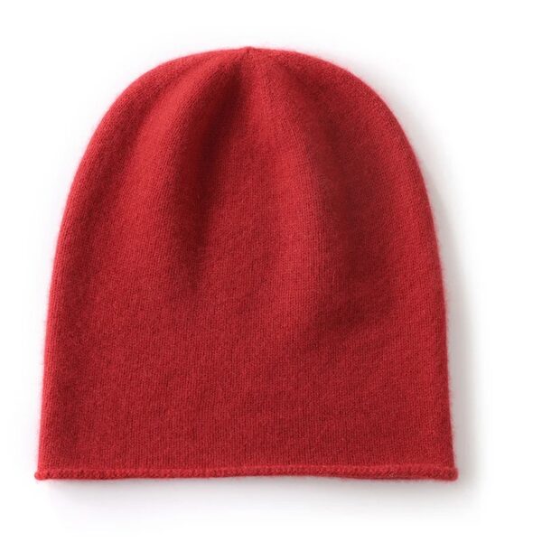 Un bonnet en cachemire de couleur rouge est présenté à plat sur un fond blanc