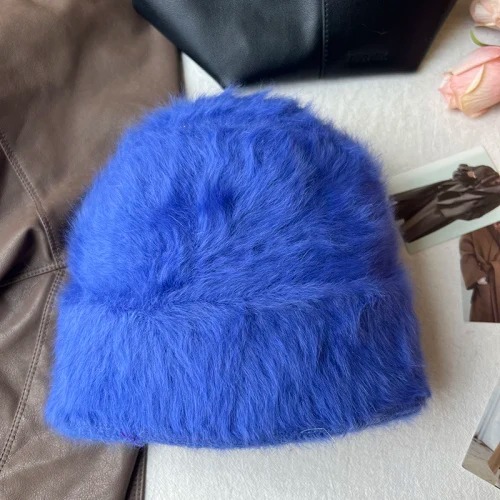 Un bonnet fourrure femme bleu est présenté sur un décor doux