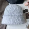 Un bonnet fourrure femme gris est présenté sur un décor doux