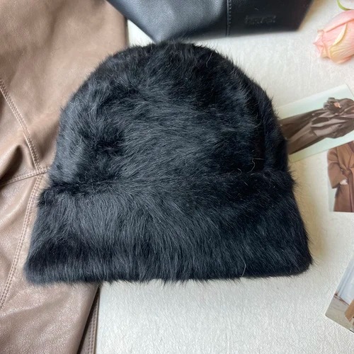 Un bonnet fourrure femme noir est présenté sur un décor doux