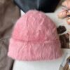 Un bonnet fourrure femme rose est présenté sur un décor doux