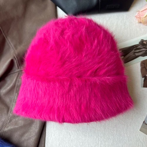 Un bonnet fourrure femme rose rouge est présenté sur un décor doux