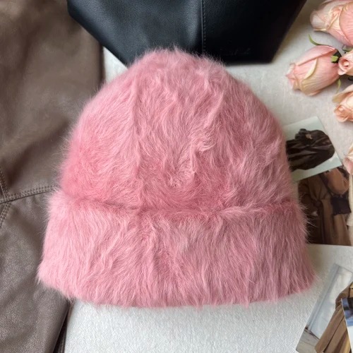 Un bonnet fourrure femme rose est présenté sur un décor doux