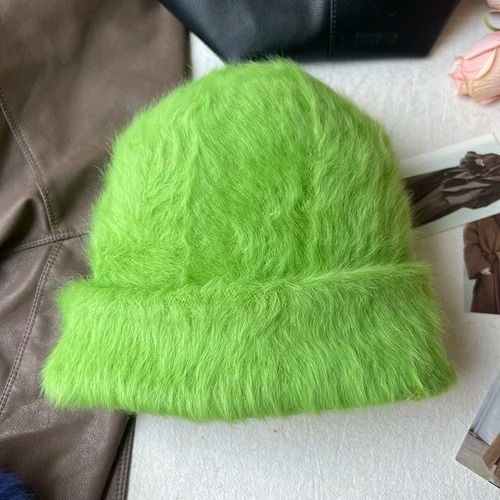 Un bonnet fourrure femme vert est présenté sur un décor doux
