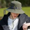 chapeau-de-pecheur-anti-uva-uvb Un homme prend la pose la tête baissée avec un bob chapeau vert anti uv sur sa tête avec un décor de verdure flouté en arrière-plan
