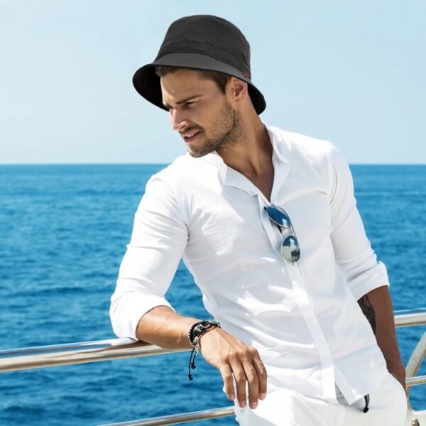 bob-chapeau-elegant-homme-moderne Un homme très élégant en chemise blanche porte un bob intemporel sous un beau ciel bleu