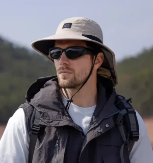 bob-passion-chapeau-randonnee-pourles-hommes-et-les-femmes Un homme style aventurier porte un bob randonnée et des lunettes de soleil sur un décor de nature