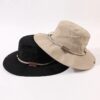 chapeau-aventure-noir-et-beige Deux couvre-chefs sont posés dans un décor clair