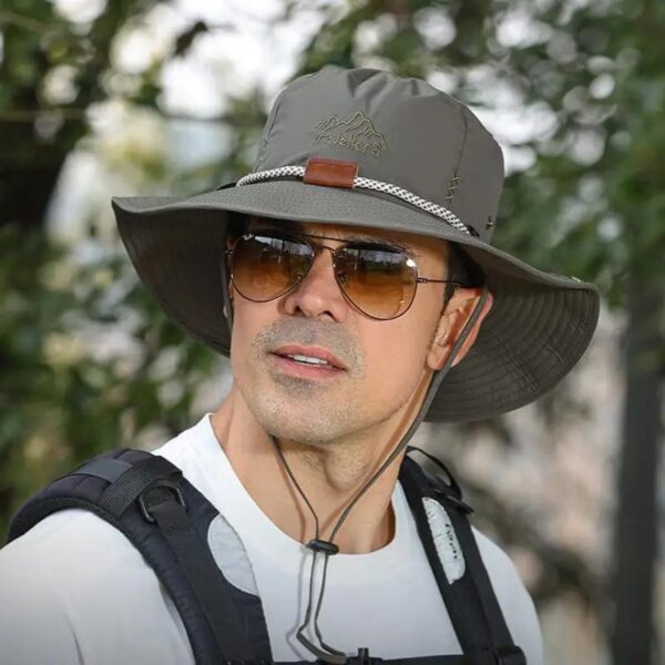 chapeau-aventurier-homme-style Un homme style explorateur porte un chapeau aventurier avec des grosses lunettes dans un décor de nature