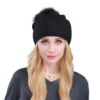 Un modèle féminin de face porte un bonnet à pompon noir sur un fond blanc