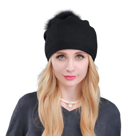 Un modèle féminin de face porte un bonnet à pompon noir sur un fond blanc