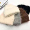 bonnet-chaud-femme-homme-lot-couleurs-laine-naturelle Plusieurs bonnets alpaga en laine naturelle de différentes couleurs, dont crème, gris, marron et noir, disposés ensemble sur une table blanche.
