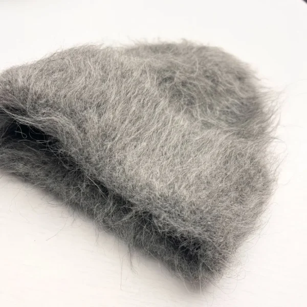 bonnet-laine-gris-hiver-style-confort-chaleur Bonnet chaud en laine grise, au toucher moelleux et chaud, posé sur une table blanche, idéal pour l’hiver et les temps froids.