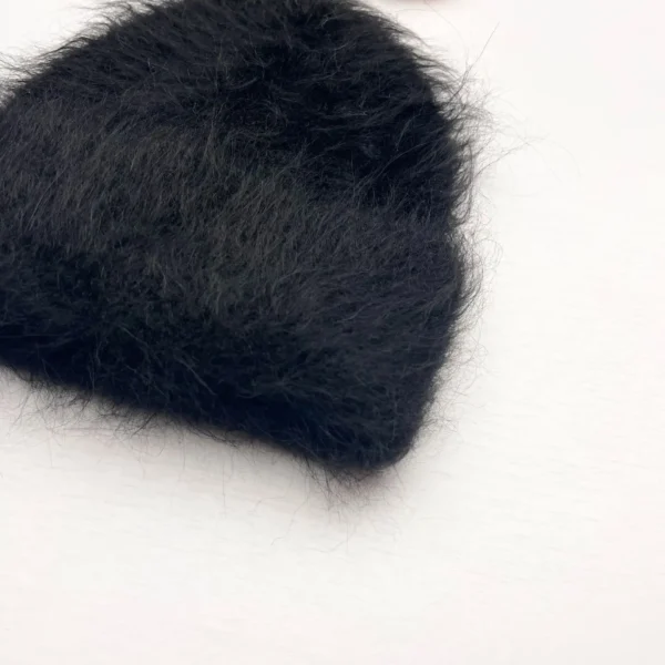 bonnet-noir-duveteux-laine-chaude-hiver Bonnet en alpaga noir avec texture duveteuse et poil long, offrant une isolation thermique élevée pour protéger du froid hivernal.