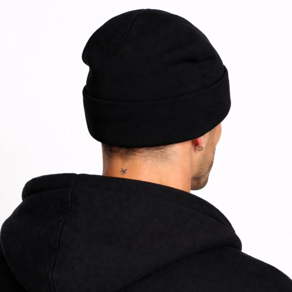 bonnet-noir-laine-hommes Un modèle porte un bonnet en laine noir de dos fond clair