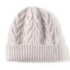 bonnet-en-laine-femme-tricot-torsades-ecru-style-hiver Bonnet en laine torsadée couleur écru pour femme, avec large revers et maille épaisse pour l’hiver.