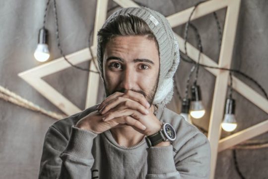 Un jeune homme porte un bonnet oversize gris sur un décor clair et épuré