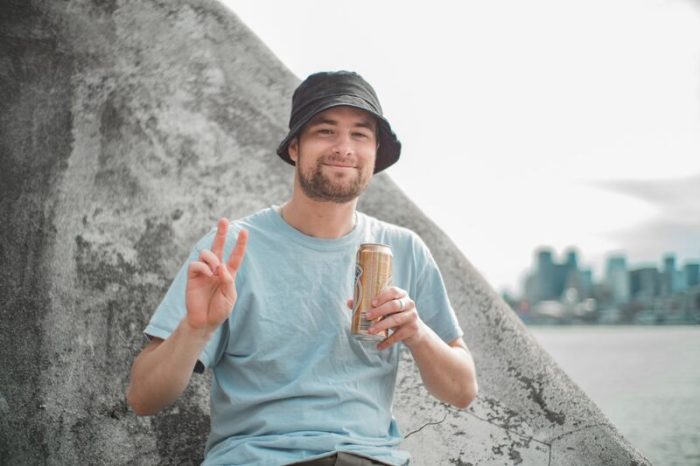 Un homme souriant à la plage porte un bob chapeau simple noir sur sa tête